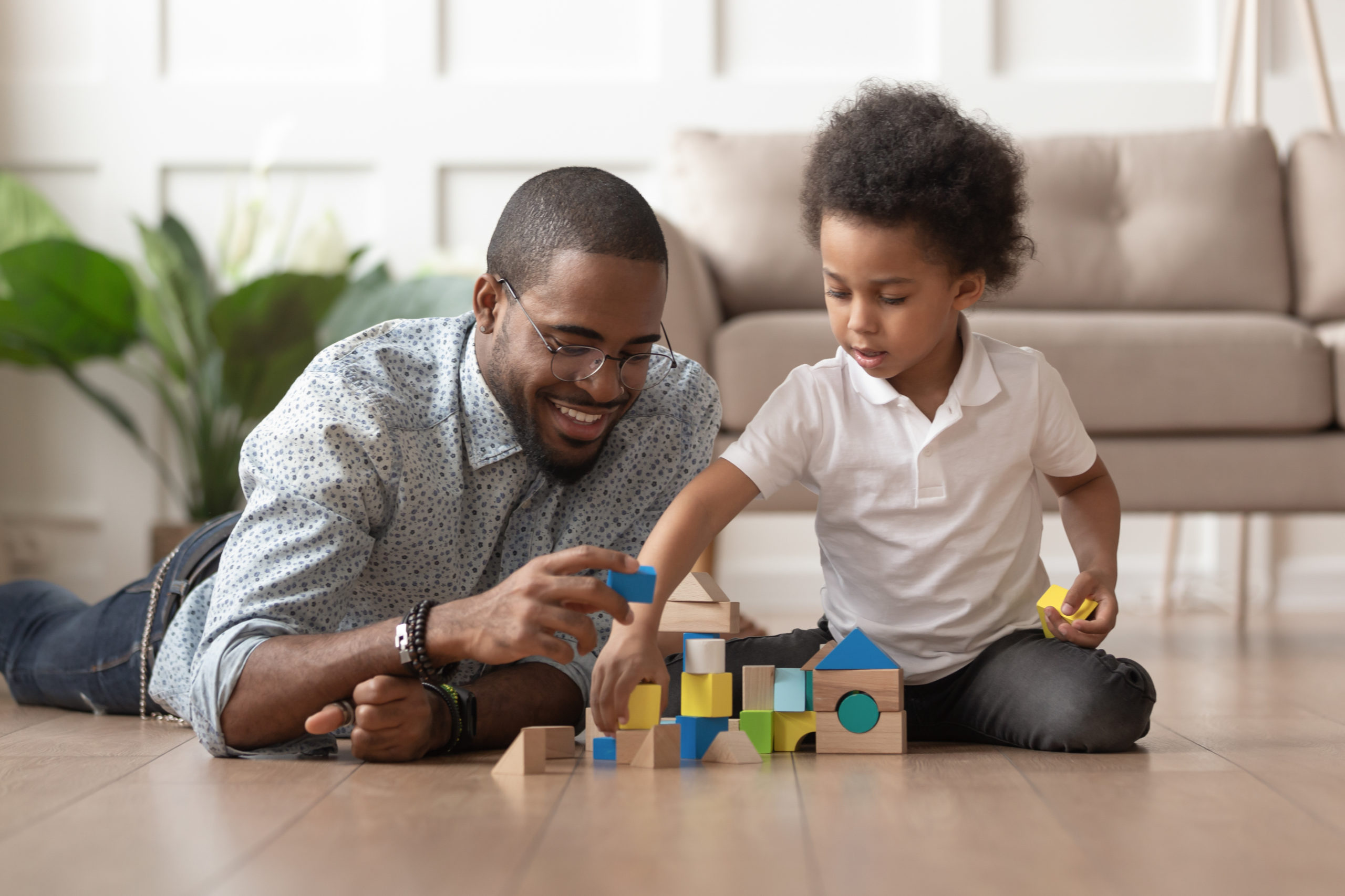 man on the floor playing with blocks with a child
