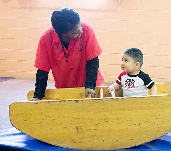 a teacher and a young toddler smile at each other